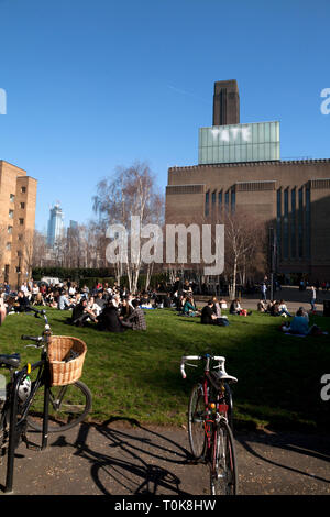 people sitting on grass otside tate modern bankside southwark london england Stock Photo