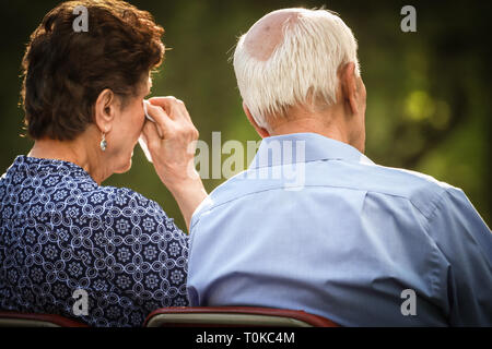 Elderly couple crying and watching sad or happy situation together. Stock Photo