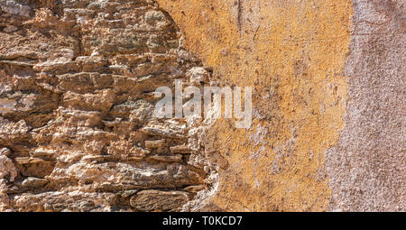 Old, distressed stone wall, building facade. Painted orange color, faded masonry texture background Stock Photo