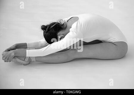 Training her flexibility. Ballet dancer doing stretching exercise. Ballerina in ballet class. Pretty woman in dance wear. Practicing classical ballet Stock Photo