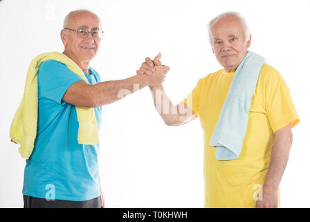 two happy smiling senior men after sport training with yellow and blue t-shirts and towels Stock Photo