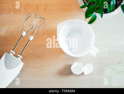 Close up of table with mixer whipped whites of eggs for cake. Whipped egg whites cream to perfect peaks in plastic bowl with mixer. Top view. Stock Photo