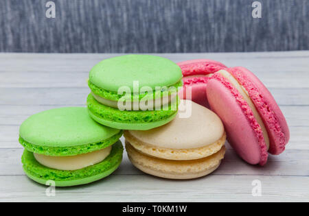 Multicolored macaroons on a wooden table, on a dark blue background Stock Photo