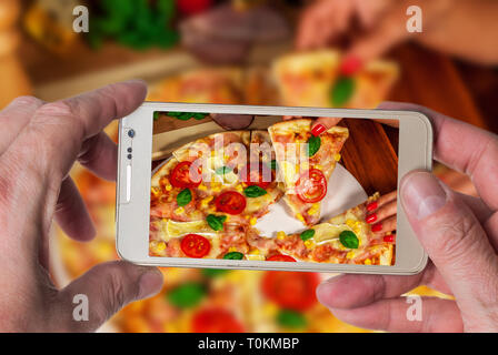 Man taking photo of Italian traditional  pizza with chesse and tomato Stock Photo
