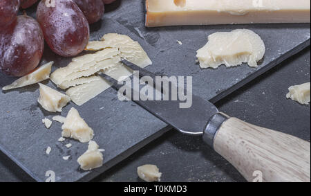 Yellow, hardand delicious cheese from Netherlands served with grapes on a stone platter. Stock Photo