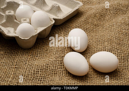 Eggs and egg carton on burlap sack cloth. Stock Photo