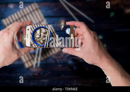 Man taking photo of Traditional asian or chines noodles with chicken meat on bowl with chopsticks on wood table Stock Photo