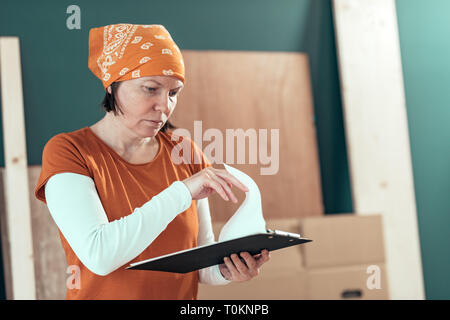 Female carpenter reading DIY project notes in small business woodwork workshop Stock Photo
