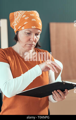 Female carpenter reading DIY project notes in small business woodwork workshop Stock Photo