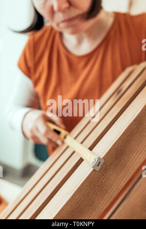 Female carpenter tape measuring wooden crate in her small business woodwork workshop Stock Photo