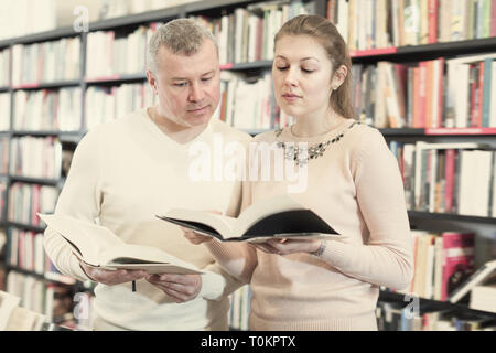 Cheerful couple choosing and discussing books in bookshop Stock Photo