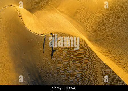 Aerial view of Woman carrying basket and children at sunset in Bau Trang sand dune, Mui Ne, Vietnam Stock Photo