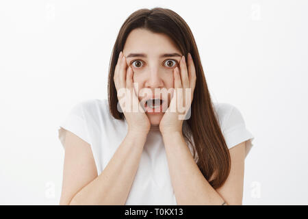 Close-up shot of shocked and speechless concerned young girl hearing shocking rumor gasping dropping jaw from unbelievable news holding hands on Stock Photo