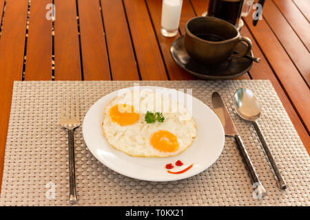 Fried egg on a white plate with coffee cup in morning breakfast. Stock Photo