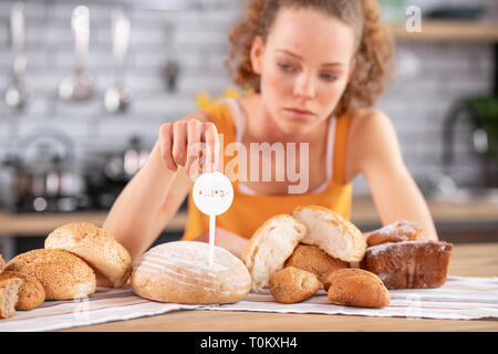 Upset long-haired woman touching allergy warning nameplate Stock Photo