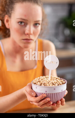 Distressed appealing woman with light eyes holding bowl with nuts Stock Photo