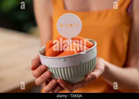Young woman holding bowl filled with mini carrots Stock Photo