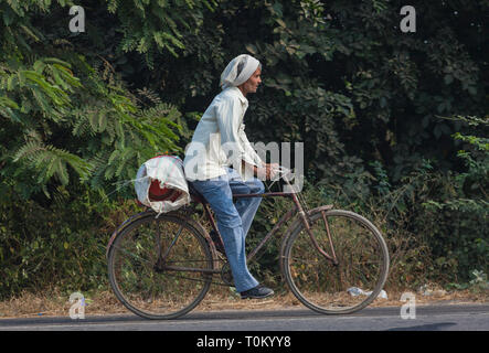 AGRA, INDIA - NOVEMBER 15, 2012: Elderly Indian man riding a bicycle through the streets of India Stock Photo