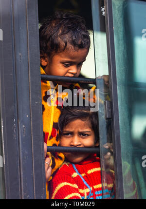 AGRA, INDIA - NOVEMBER 15, 2012: Indian poor dirty kids ride the train and look out the window. Poor and rich Indian life Stock Photo