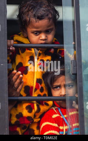 AGRA, INDIA - NOVEMBER 15, 2012: Indian poor dirty kids ride the train and look out the window. Poor and rich Indian life Stock Photo