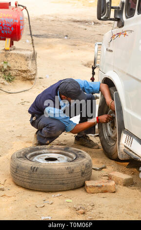 AGRA, INDIA - NOVEMBER 16, 2012: Man repairing car wheel in india Stock Photo