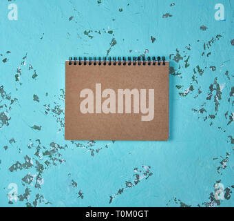empty notebook on a black iron spring with brown empty sheets on a green background, close up Stock Photo