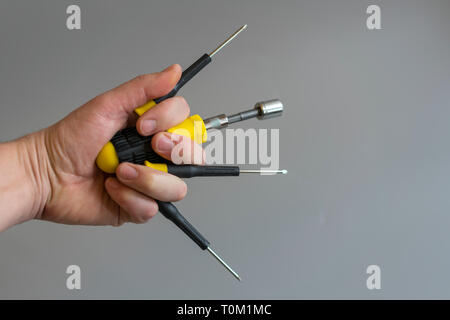 Hands raised holding different tools. Male hands with different repair tools on gray background. copy space. Stock Photo