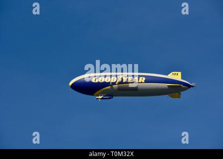 Famous Goodyear blimp dirigible soaring overhead in flight in bright blue sky, outside sporting event, PGA golf tournament, San Diego, CA, USA. Stock Photo