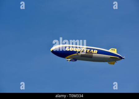 Famous Goodyear blimp dirigible soaring overhead in flight in bright blue sky, outside sporting event, PGA golf tournament, San Diego, CA, USA. Stock Photo