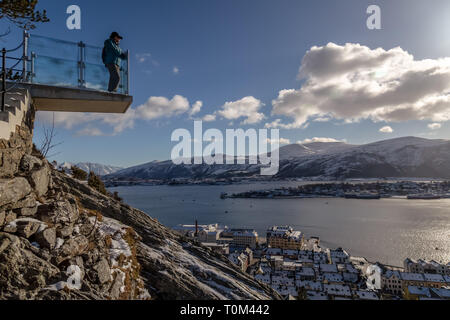 A female tourist looks out from a viewing platform, looking over the town of Alesund in Norway. Stock Photo