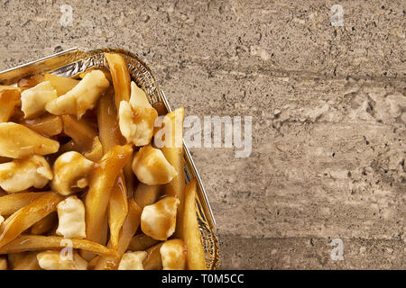 Poutine in a takeout container. Cooked with french fries, beef gravy and curd cheese. Copy space for your text. Stock Photo
