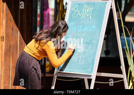 A young pretty Mexican woman writing buffet menu on a board outside a  Mexican restaurant in Cholula Puebla Mexico Stock Photo - Alamy
