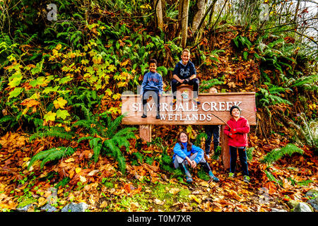 Cousins sitting on the sign at the entrance to Silverdale Creek Wetlands, a freshwater Marsh and Bog near Mission, BC on a nice fall day Stock Photo