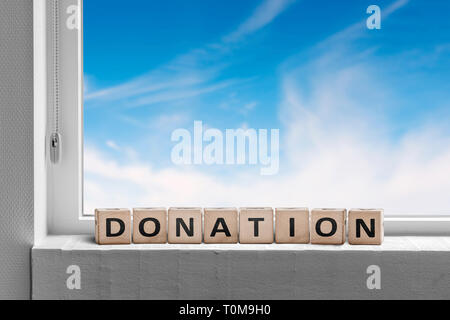 Donation sign standing in a window with a blue heaven outside Stock Photo