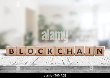 Blockchain sign made of wood on a desk in a bright living room Stock Photo