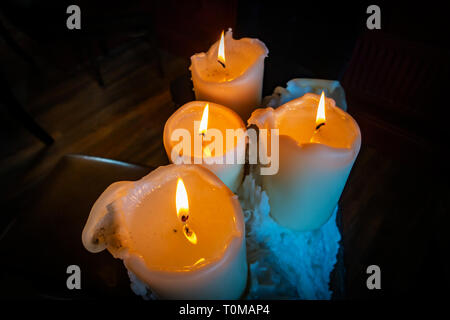 wonderful cluster of beautiful old church style candles perched on the top of a very large pile of old melted candle wax drippings Stock Photo