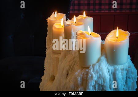 wonderful cluster of beautiful old church style candles perched on the top of a very large pile of old melted candle wax drippings Stock Photo