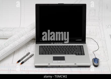 Computer with architectural plans lying on table Stock Photo