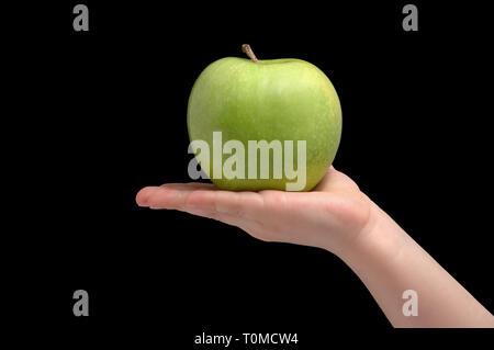 Green ripe apple on woman palm. Isolated black background.