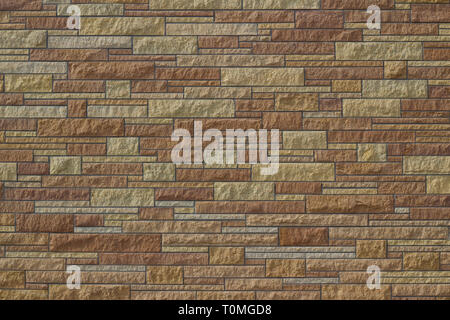 Beautiful modern limestone brick wall background in varying shades of brown and different sizes and shaped stone blocks Stock Photo