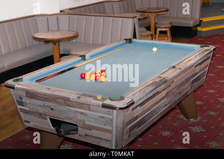 Pool table with racked balls and cue in a leisure venue interior. Stock Photo
