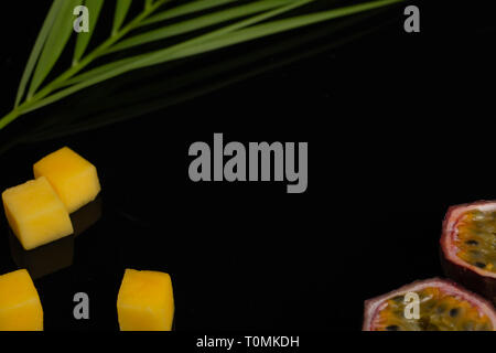 a peeled diced pineapple, bamboo and passion fruit. Fresh Tropical Fruits. On a black background. Top view. Copy space. Stock Photo