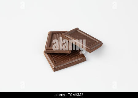 close up of chocolate pieces stack and chocolate syrup on white background. milk chocolate Stock Photo