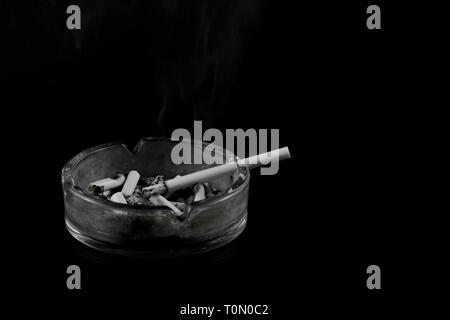 Cigarette on full smoked ashtray on black background Stock Photo