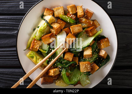 Asian veggie fried tofu with bok cho and sesame close-up on a plate on the table. Horizontal top view from above Stock Photo