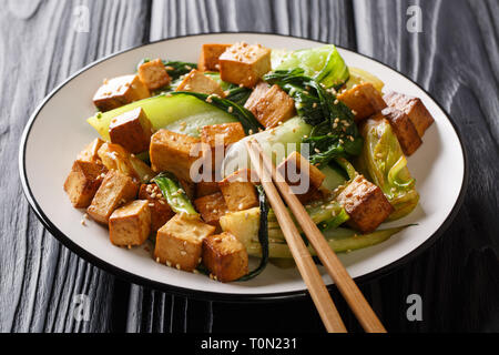 Dietary stir fried tofu with baby bok choy, soy sauce and sesame seeds closeup on a plate on the table. horizontal Stock Photo