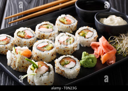 Uramaki rolls set served with sauces, soy sprouts, ginger and wasabi closeup on a plate on the table. horizontal Stock Photo