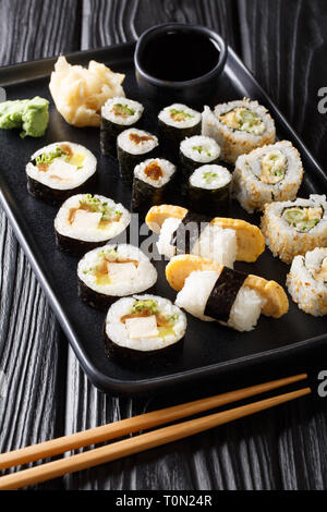 Japanese rolls Hosomaki, Uramaki, Maki, Nigiri, Tamagoyaki with various fillings close-up on a plate on the table. vertical Stock Photo