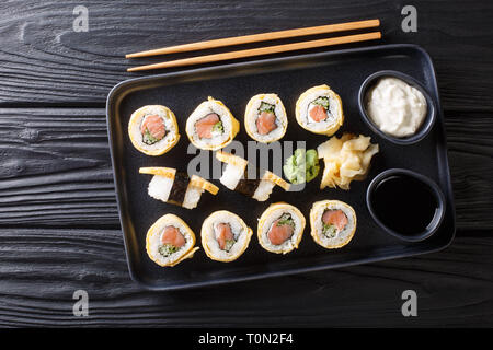 Tamagoyaki sushi roll with rice, cheese, salmon and avocado closeup on a plate on the table. Horizontal top view from above Stock Photo