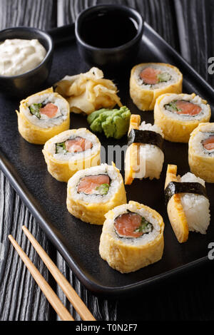 Japanese breakfast set tamagoyaki sushi roll with rice, cheese, salmon and avocado closeup on a plate on the table. vertical Stock Photo